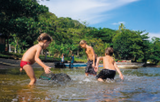 IMAGEM: três crianças brincam em um rio. FIM DA IMAGEM.