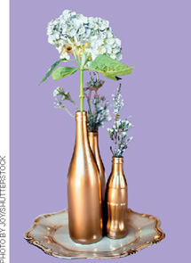 IMAGEM: garrafas de três tamanhos, pintadas de dourado, com flores. FIM DA IMAGEM.