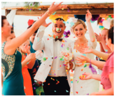 IMAGEM: um casal de noivos caminham sorridentes, enquanto os convidados jogam pedacinhos de papéis coloridos sobre eles. FIM DA IMAGEM.