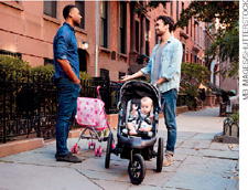 IMAGEM: dois homens, com carrinhos de bebê, conversam em uma calçada. FIM DA IMAGEM.