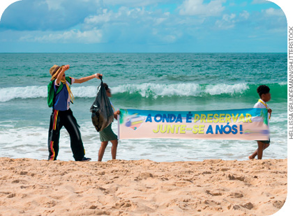 IMAGEM: pessoas andam na praia carregando uma faixa que diz: a onda é preservar. junte-se a nós. FIM DA IMAGEM.
