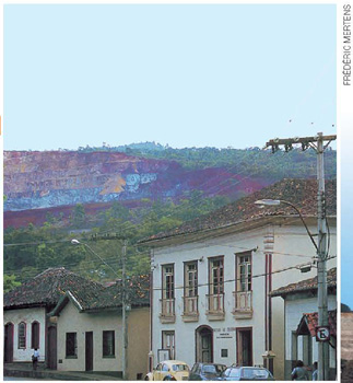 IMAGEM: fotografia colorida de uma montanha escavada, com pouca vegetação. abaixo, fachadas de quatro casas. FIM DA IMAGEM.