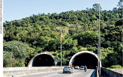 IMAGEM: fotografia de dois túneis sob uma montanha, por onde passa uma rodovia. FIM DA IMAGEM.