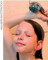 IMAGEM: uma criança de olhos fechados segura uma ducha sobre a cabeça. FIM DA IMAGEM.