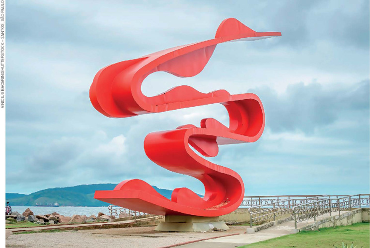 IMAGEM: estrutura escultural de grandes dimensões, localizada próxima ao mar, com o formato de uma fita recurvada, o que lhe confere um aspecto leve, mesmo sendo feita de aço. FIM DA IMAGEM.