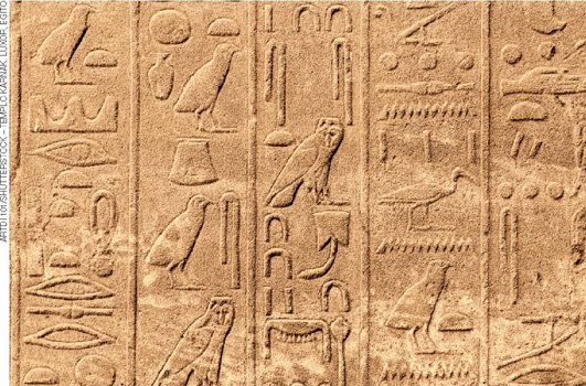 IMAGEM: parte de uma parede com inscrições hieroglíficas. os hieróglifos são dispostos na pedra em colunas. há figuras de pássaros, olhos e outros grafismos. as colunas estão separadas por linhas. FIM DA IMAGEM.