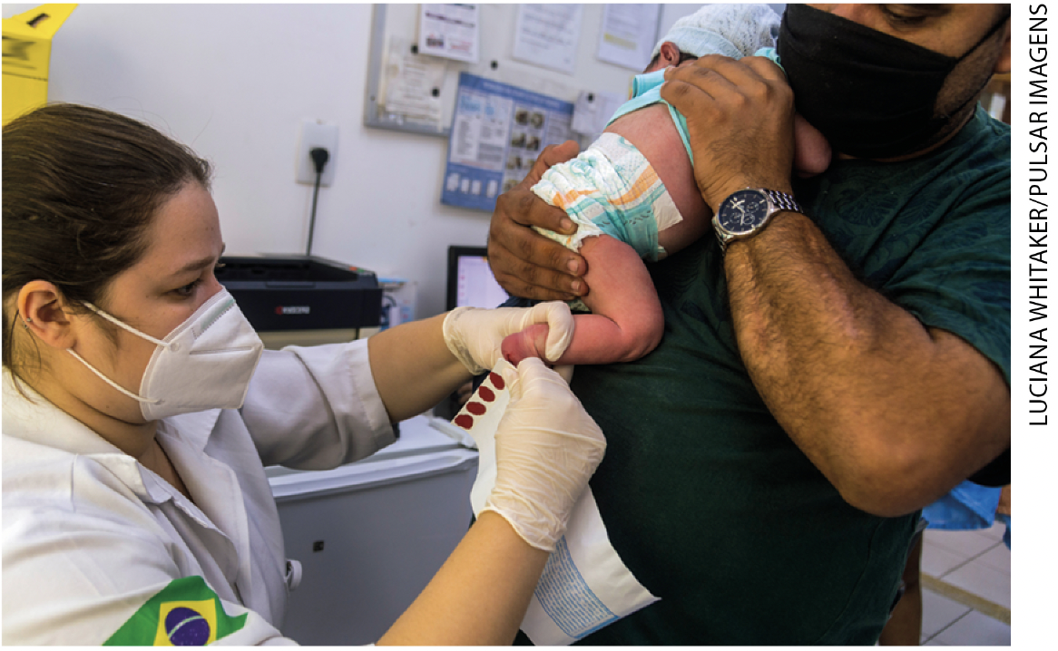 IMAGEM: item c. uma profissional da saúde com máscara e luvas aplica vacina na perna de um bebê, que está no colo de um homem, também de máscara. FIM DA IMAGEM.