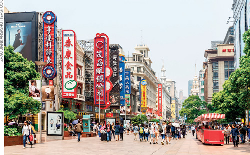 IMAGEM: rua com um grande fluxo de pessoas, há muitos prédios ao redor com letreiros na vertical coloridos e com símbolos chineses. FIM DA IMAGEM.