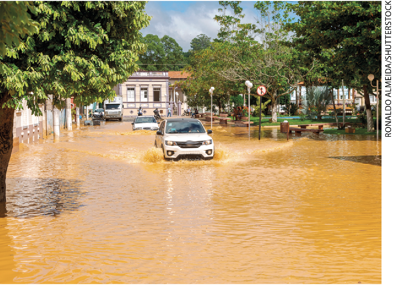 IMAGEM: carro andando por uma rua inundada com água. FIM DA IMAGEM.