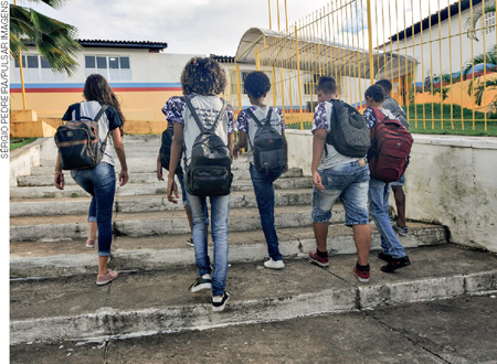IMAGEM: adolescentes caminham em direção à escola. . FIM DA IMAGEM.