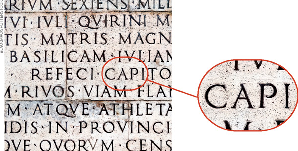IMAGEM: escritos em latim, sobre uma parede de pedra. uma lupa destaca seus detalhes. . FIM DA IMAGEM.