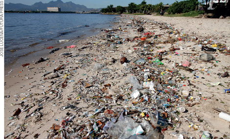 IMAGEM: praia com lixo em sua extensão. há embalagens, sacos plásticos, garrafas e entre outros acumulados próximos ao mar. FIM DA IMAGEM.