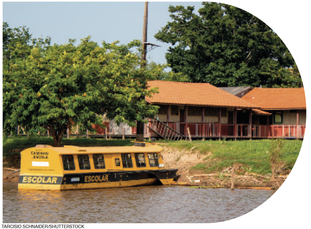 IMAGEM: um barco preto e amarelo com uma faixa escrita escolar, atracado nas margens de um rio. ao fundo, há duas construções, um gramado e árvores. FIM DA IMAGEM.