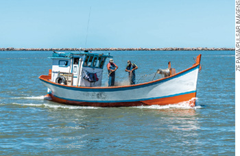 IMAGEM: homens pescam com redes em um barco no meio do oceano. FIM DA IMAGEM.