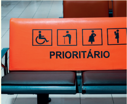 IMAGEM: Dois assentos sinalizados como prioritário. No estofado há quatro figuras que representam uma pessoa em cadeira de rodas, um idoso de bengala, uma mulher grávida e uma mulher com criança pequena no colo. FIM DA IMAGEM.