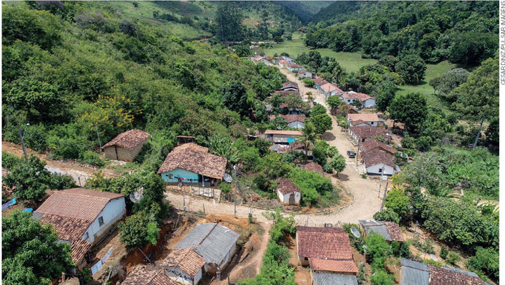 IMAGEM: a fotografia aérea mostra uma comunidade quilombola entre dois morros cheios de vegetação. diversas casas de concreto foram construídas em uma única rua que corta o vale. FIM DA IMAGEM.
