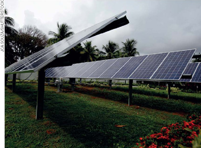 IMAGEM: painéis de geração de energia solar colocados sobre uma estrutura de metal em um gramado e inclinados para cima. FIM DA IMAGEM.
