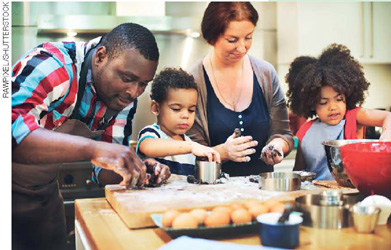 IMAGEM: um pai, uma mãe, uma filha e um filho estão cozinhando no balcão de uma cozinha. FIM DA IMAGEM.