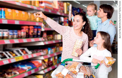 IMAGEM: um pai, uma mãe e duas filhas estão fazendo compras no supermercado. o pai carrega uma das filhas, enquanto a mãe escolhe produtos na prateleira com a outra menina. FIM DA IMAGEM.