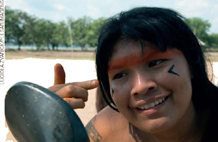 IMAGEM: mulher indígena pintando o rosto com tinta vermelha e preta. FIM DA IMAGEM.