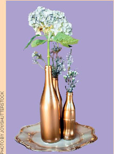 IMAGEM: flores dentro de vasos feitos com garrafas de vidro de diferentes tamanhos. FIM DA IMAGEM.