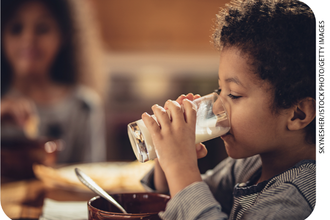 IMAGEM: 2. uma criança pequena bebe um copo de leite. FIM DA IMAGEM.