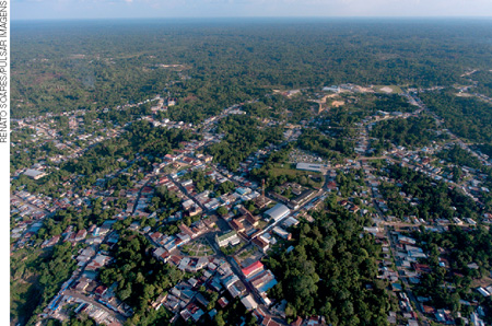 IMAGEM: vista aérea de um município com construções dentro de uma área de floresta. FIM DA IMAGEM.