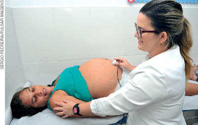 IMAGEM: uma médica examina uma paciente grávida. FIM DA IMAGEM.