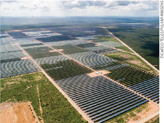IMAGEM: vista aérea de uma usina de energia solar com painéis solares de grande extensão. FIM DA IMAGEM.