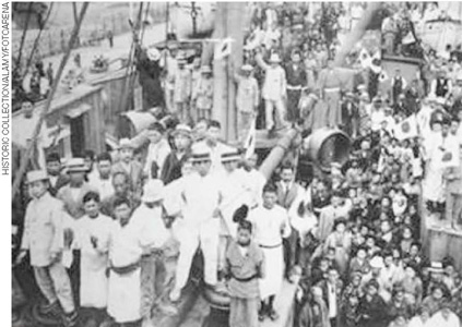 IMAGEM: um numeroso grupo de pessoas japonesas aglomeradas em uma embarcação marítima. alguns usam chapéu e terno. outros estão trajados com quimono. FIM DA IMAGEM.