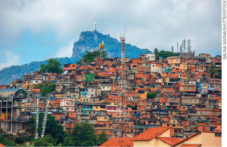 IMAGEM: vista de uma favela, com centenas de casas em um morro e o corcovado ao fundo. FIM DA IMAGEM.