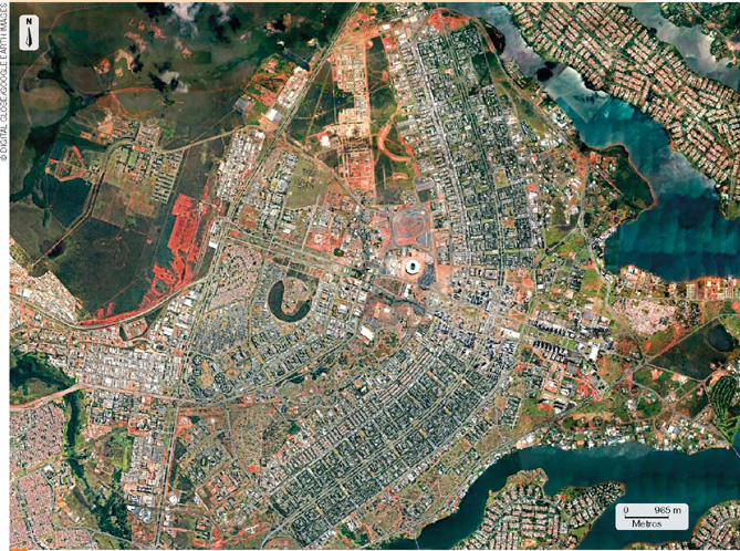 IMAGEM: uma fotografia de satélite mostra que a cidade de brasília tem o formato similar ao contorno de um avião. a escala da imagem de satélite é de cerca de uma polegada, correspondente a 905 metros. um ícone no canto superior da imagem indica a direção norte, com uma seta para baixo. FIM DA IMAGEM.