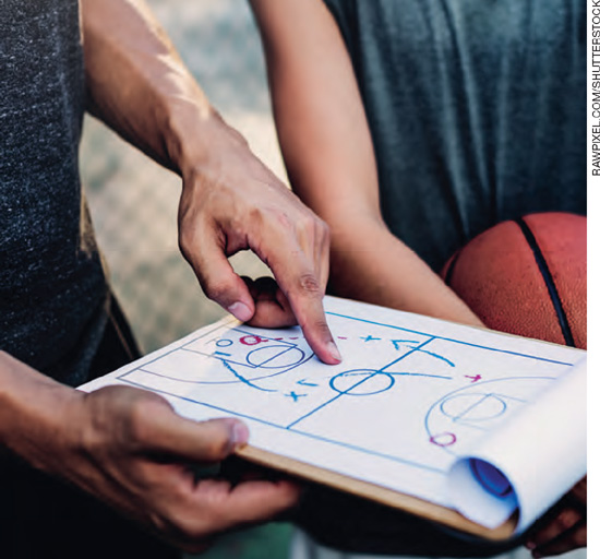 IMAGEM: uma pessoa segura uma prancheta que apresenta um esquema para o planejamento de jogadas de basquete. FIM DA IMAGEM.