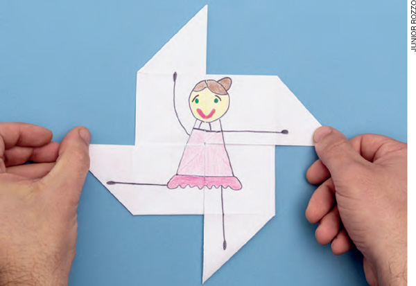 IMAGEM: uma pessoa segura uma dobradura de papel em que está desenhada uma bailarina. FIM DA IMAGEM.