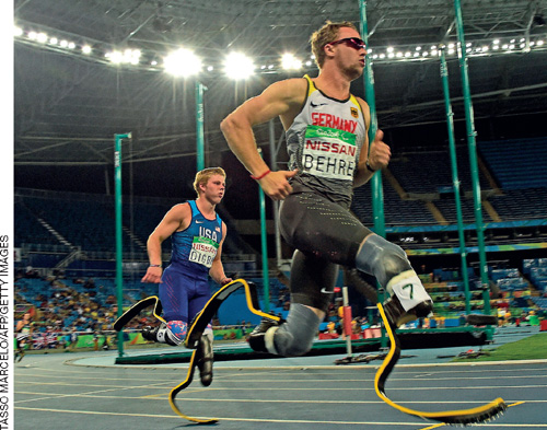 IMAGEM: dois atletas paralímpicos competem em uma pista de corrida. eles não têm as duas pernas, e usam próteses esportivas. FIM DA IMAGEM.