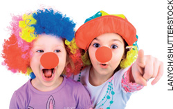 IMAGEM: duas crianças vestidas de palhaço. elas usam peruca colorida, chapéu e um nariz vermelho redondo de plástico. FIM DA IMAGEM.