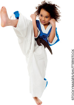 IMAGEM: uma menina vestida com um quimono dá um chute alto, no ar. ela está com os braços flexionados em posição de defesa. FIM DA IMAGEM.