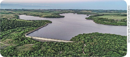 IMAGEM: imagem aérea de barragem e seus arredores com vegetação e planícies. FIM DA IMAGEM.