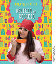 IMAGEM: reprodução da capa do livro delícia de recreio, contendo a fotografia de uma chefe de cozinha segurando uma grande colher com alimento. FIM DA IMAGEM.