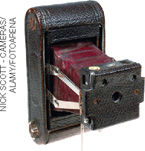 IMAGEM: máquina fotográfica antiga. a estrutura que contém a lente é projetada para frente por uma peça sanfonada. FIM DA IMAGEM.