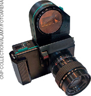 IMAGEM: máquina fotográfica digital com uma grande lente na parte frontal e uma em sua parte superior. FIM DA IMAGEM.