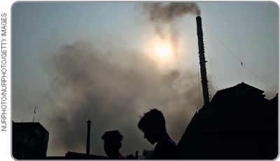 IMAGEM: chaminés de uma fábrica despejam fumaça tóxica no ar. FIM DA IMAGEM.