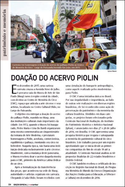 Imagem: Fotografia. Página de revista. Na parte superior, foto de pessoas sentadas em carros abertos com as mãos para cima e segurando bandeiras coloridas. Abaixo, o título: DOAÇÃO DO ACERVO PIOLIN e em seguida, textos. Fim da imagem.