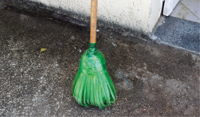 Imagem: Fotografia. Uma vassoura feita de garrafa PET verde. Fim da imagem.