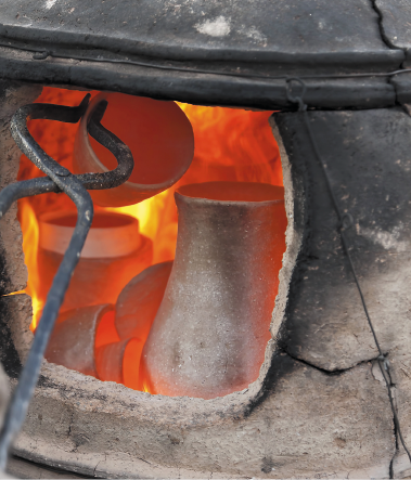 Imagem: Fotografia. Peças de argila cinza dentro de um forno. Fim da imagem.