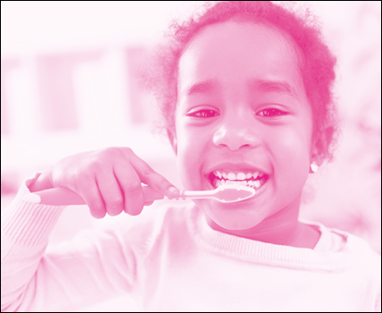 Imagem: Fotografia em tons de rosa. Menina de cabelo cacheado, vestindo camiseta de manga longa. Está escovando os dentes. Fim da imagem.
