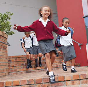 Imagem: Fotografia. Crianças descendo uma escada de uniforme com mochilas. Fim da imagem.