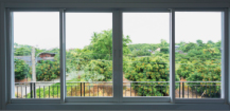 Imagem: Fotografia. Janela com vidros transparentes com vista para árvores de plantação. Fim da imagem.