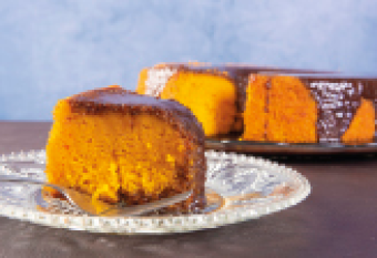 Imagem: Fotografia. Corte de bolo de cenoura com cobertura de chocolate. Fim da imagem.
