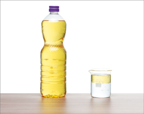 Imagem: Fotografia. Vidro de óleo. Ao lado, copo com camada de água inferior e camada de óleo superior. Fim da imagem.